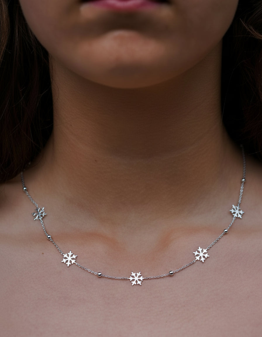Silver necklace with snowflake pendants on a person's neck
